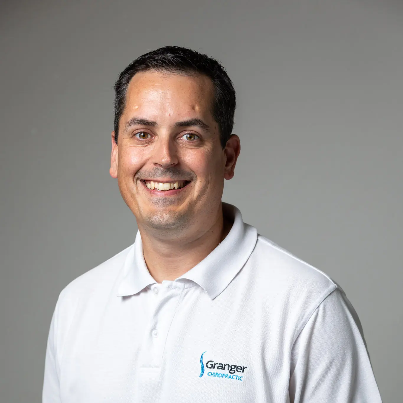 Man smiling in white polo shirt